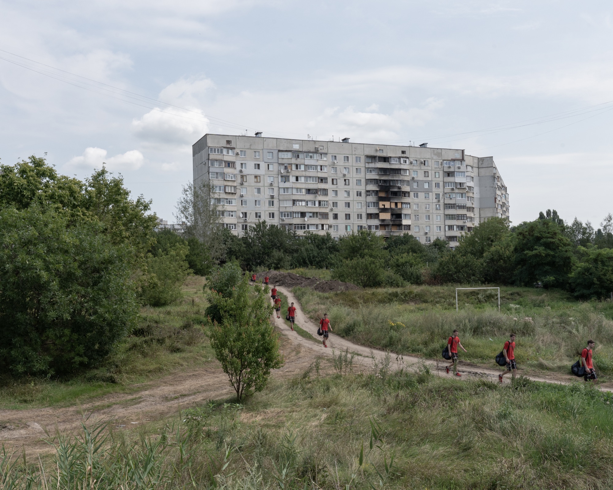 Багатоповерхівка й люди на стежці серед зелені